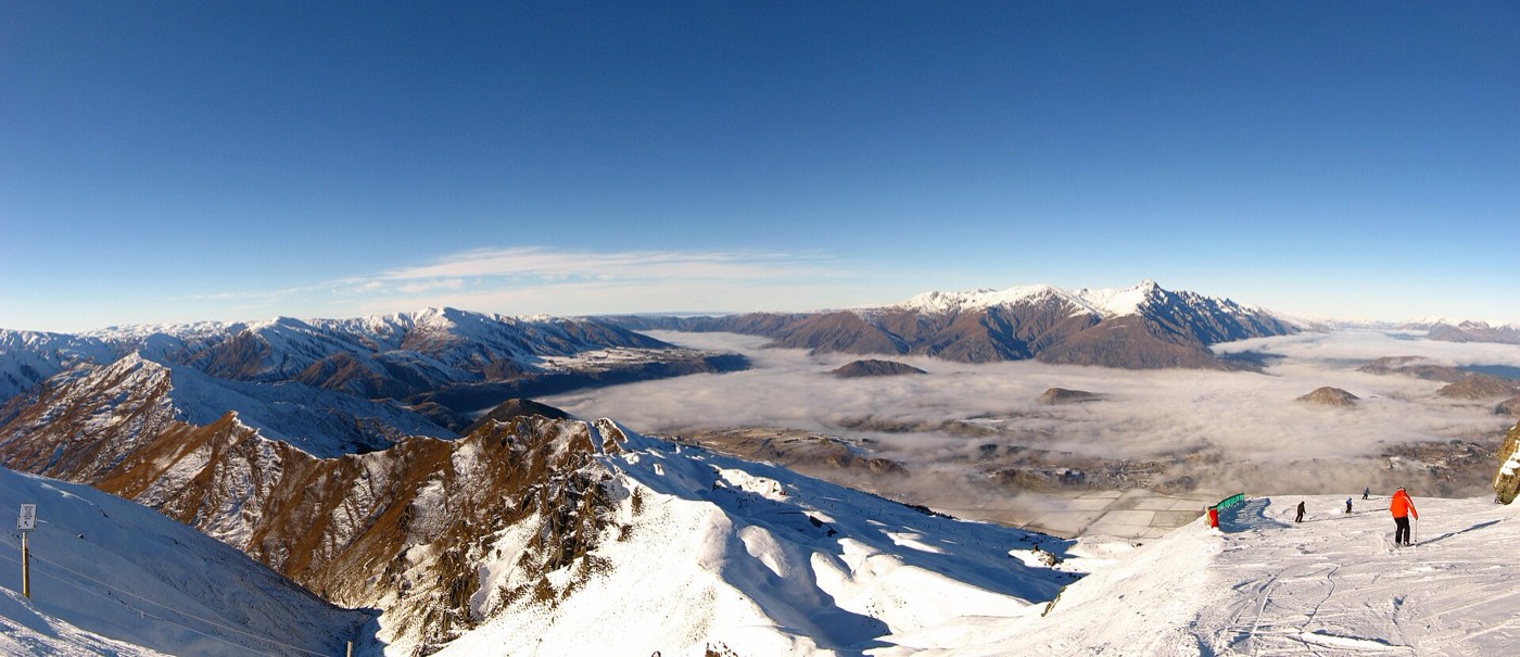 Coronet Peak 雪場的雪坡與滑雪者，山谷間有雲海